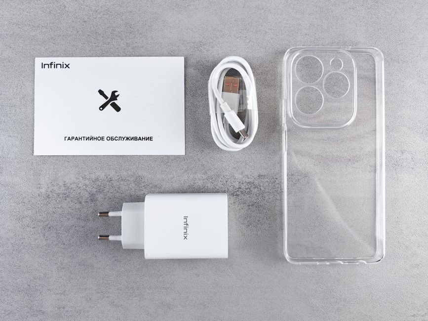 An organized flat lay of smartphone accessories on a grey surface, including a white Infinix branded charger with two prongs, a neatly coiled white USB-C charging cable, a transparent plastic phone ca