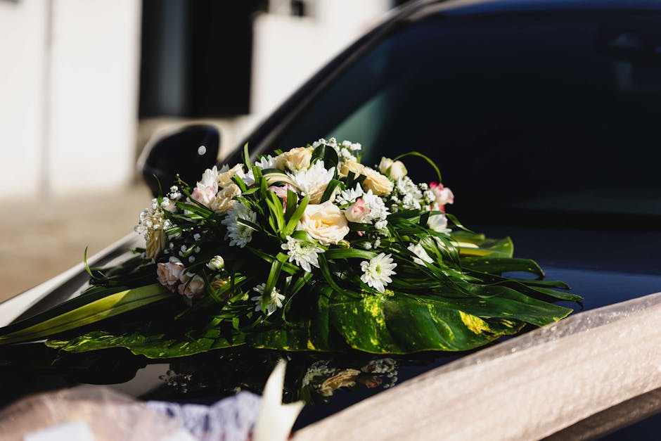 A fresh floral arrangement featuring a bouquet of white and pale pink roses, white daisies, and small white baby's breath, accented with lush green foliage. The bouquet is beautifully arranged with th